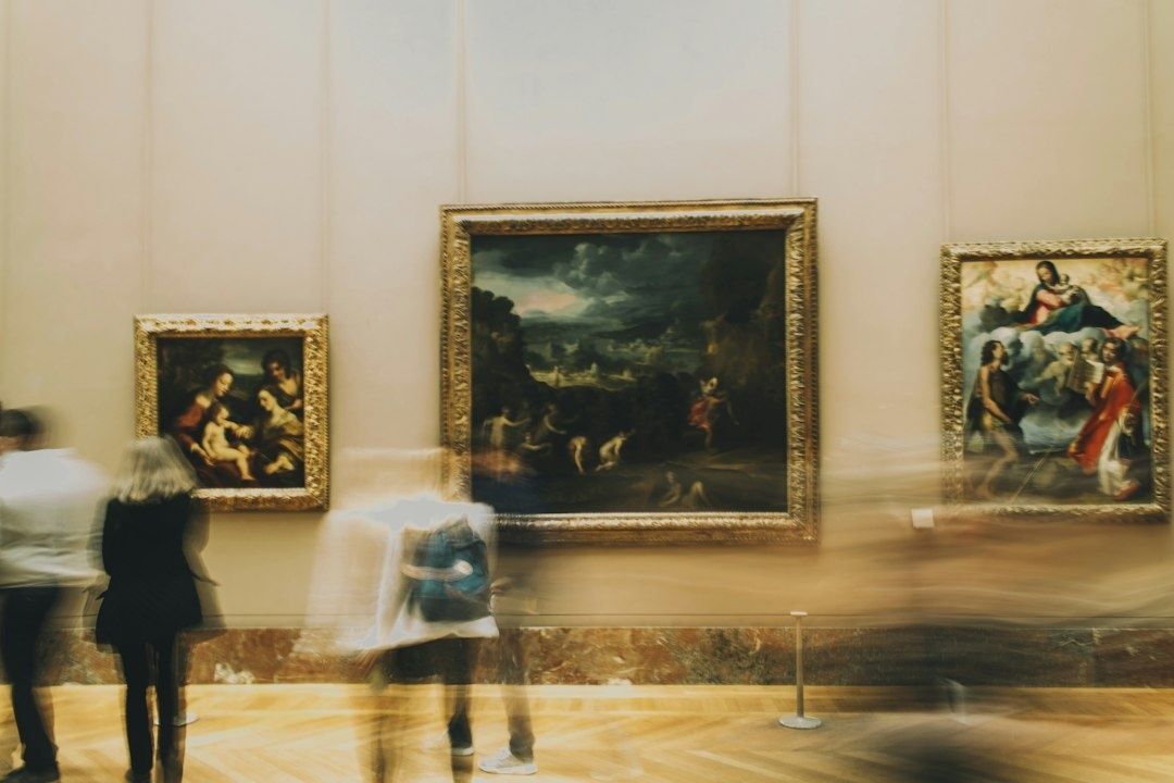 Bezoekers bekijken schilderijen in een museumzaal, met een schetsboek