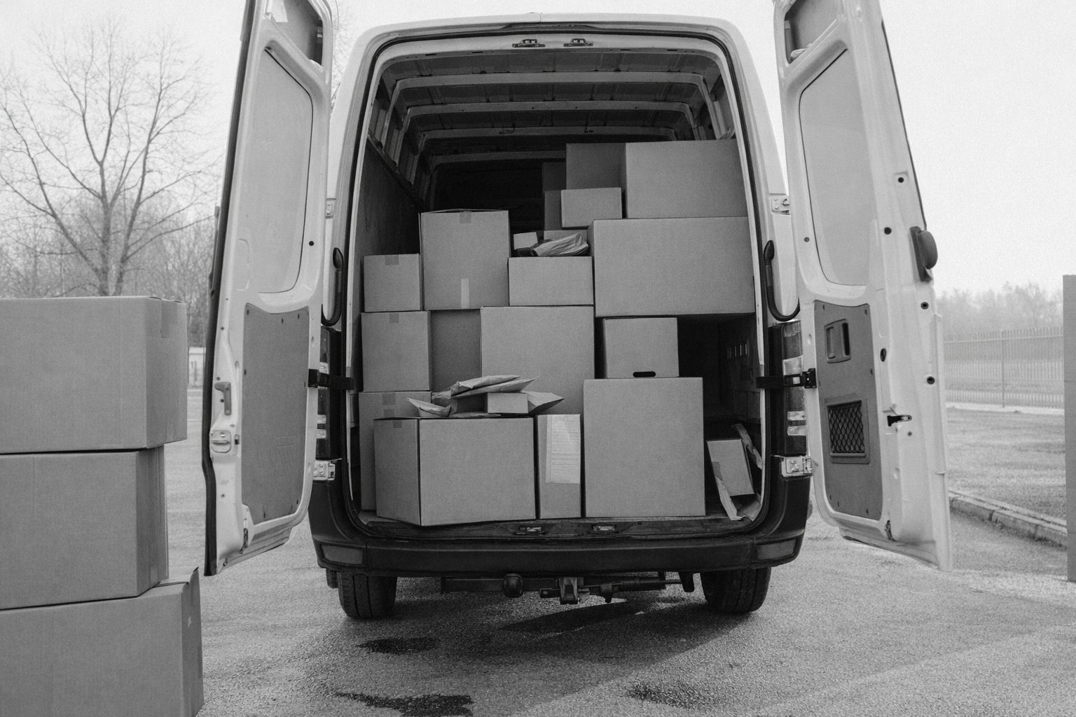 Zijaanzicht van een witte bestelwagen volgestapeld met kartonnen dozen voor transport.